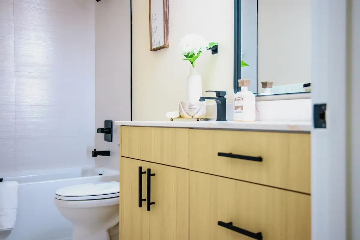 Light bath vanity with decorative vase and softly lit wall