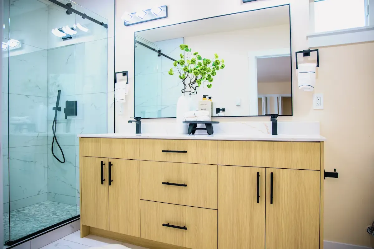 Glass shower and crisp countertops with sculptural greenery